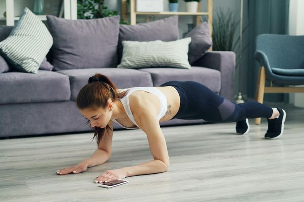 Man performing a plank exercise with correct form on a yoga mat in a spacious room.